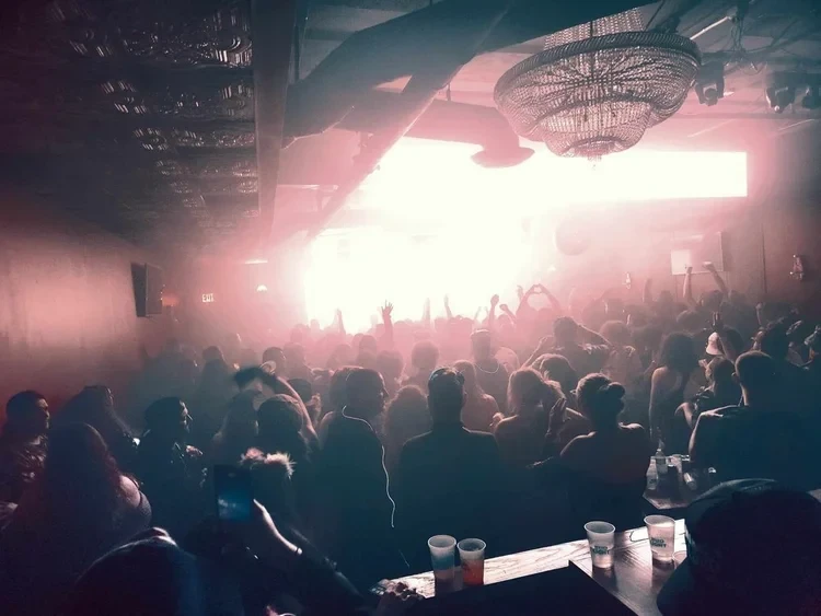 Packed crowd at Photo City Music Hall with pink stage lighting